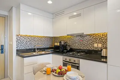 a kitchen with a table with a bowl of fruit on it at DAMAC Aykon Tower - High-Floor Luxury 2-Bedroom Apartment in Dubai