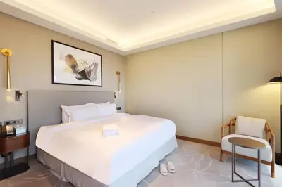 a bedroom with a large white bed and a chair at 3B in Downtown with Burj Khalifa View Near Dubai Mall and Opera District in Dubai