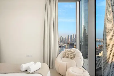 a living room with a chair and a window at FIRST CLASS 2BR Marina, Sea & Ain Views in Dubai