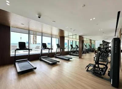 a gym with cardio equipment in a building with windows at Modern Studio Apartment in Binghatti Tulip with Pool, Parking, Gym in Dubai