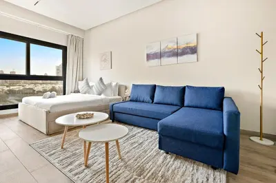 a living room with a blue couch and a bed at FIRST CLASS Studio Charming Cozy Comfort in Dubai