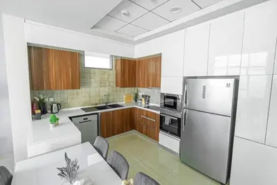 a white kitchen with a table and a refrigerator at Executive 4BR Townhouse - Al Furjan in Dubai