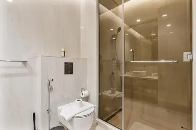 a white bathroom with a shower and a toilet at Elegant Studio with Iconic Burj Khalifa Views in Dubai