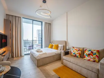 a living room with a bed and a couch at Dubai Miracle Garden Modern Luxury Studio Pool, Padel Court & Sauna Arjan in Dubai