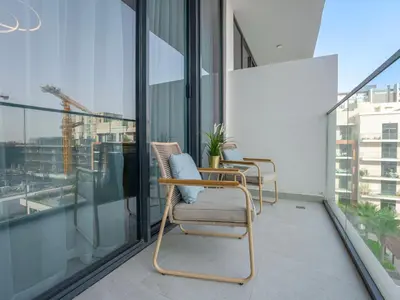 a balcony with two chairs and glass windows at Dubai Miracle Garden Modern Luxury Studio Pool, Padel Court & Sauna Arjan in Dubai