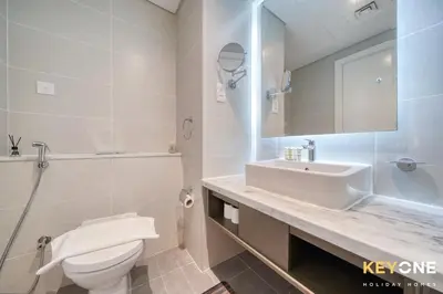 a white bathroom with a sink and a toilet at Sleek Studio in Privé with Stunning Canal View in Dubai