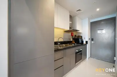 a kitchen with white cabinets and stainless steel appliances at Sleek Studio in Privé with Stunning Canal View in Dubai