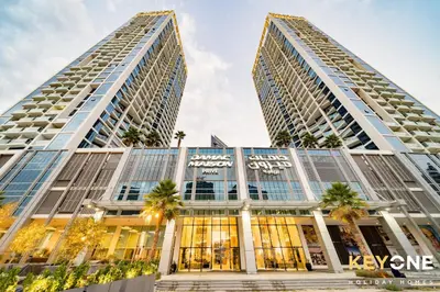 two tall buildings with palm trees in front of them at Sleek Studio in Privé with Stunning Canal View in Dubai