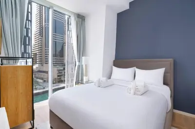 a bedroom with a large white bed with a large window at Marina | Canal View Studio in Cayan Tower in Dubai