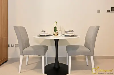 a table with two chairs and a white table with a plate at Luxury Studio in Dubai Hills by Deleguest in Dubai