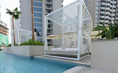 a whitevisorvisor chair sitting next to a swimming pool at Luxury 1BR W Private Pool Binghatti Royale in Dubai