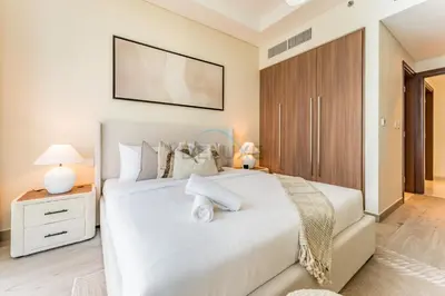 a bedroom with a white bed and a wooden cabinet at Elegant 3BR, Skyline Retreat in Downtown Dubai - Imperial Avenue, Downtown Dubai by Deluxe Holiday Homes in Dubai