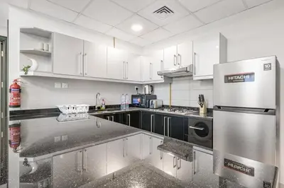 a kitchen with white cabinets and a stainless steel refrigerator at Spacious 1BR Elite Business Bay Residence in Dubai