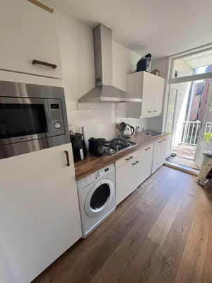 a kitchen with white cabinets and a washer and dryer at Skyline Breeze Living in Dubai