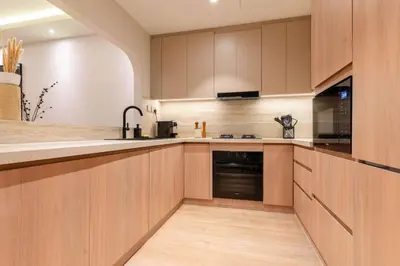 a kitchen with wooden cabinets and a black appliance at 1BR Plus Studio Apartment With Burj View In Downtown Dubai in Dubai
