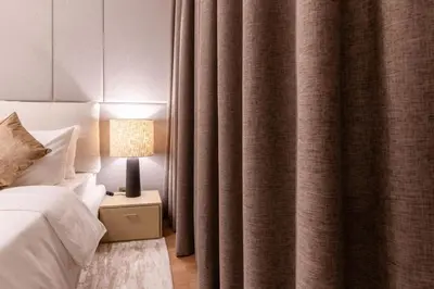 a bedroom with a bed and a lamp and curtains at 1BR Plus Studio Apartment With Burj View In Downtown Dubai in Dubai