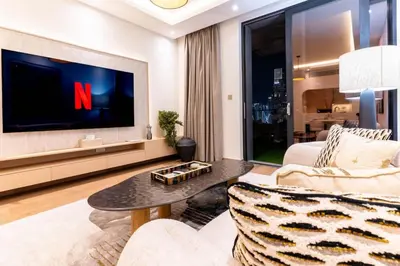 a living room with a tv and a couch and a table at 1BR Plus Studio Apartment With Burj View In Downtown Dubai in Dubai
