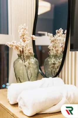 a table with a mirror and two vases with flowers at 4 Bedroom Burj View Apartment In Downtown Dubai in Dubai