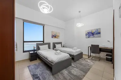a bedroom with two beds and a desk and a window at Beachfront JBR Stunning Views, Pool & Gym in Dubai