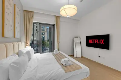 a bedroom with a white bed and a tv at Creek Beach Getaway Lagoon, Pool & Gym Access in Dubai