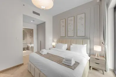 a white bedroom with a large bed and a bathroom at Creek Beach Getaway Lagoon, Pool & Gym Access in Dubai
