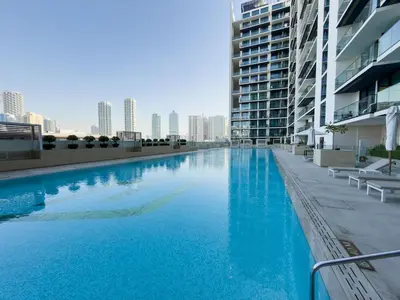 a large blue swimming pool in front of a building at Luxurious JVC Getaway Infinity Pool & Gym in Dubai