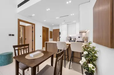 a kitchen and living room with a table and chairs at Luxurious JVC Getaway Infinity Pool & Gym in Dubai