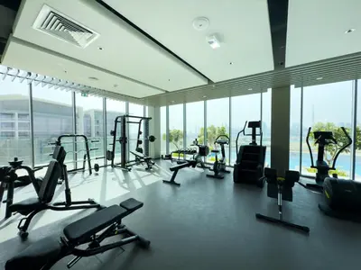 a gym with treadmills and ellipticals in a building with windows at Urban Haven Pool, Gym & Spectacular Views in Dubai
