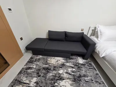 a black couch in a room with a bed at 21 Studio in Skyz by Danube, Arjan in Dubai