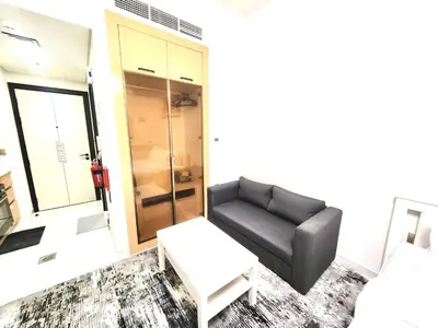 a living room with a black couch and a stool at 21 Studio in Skyz by Danube, Arjan in Dubai