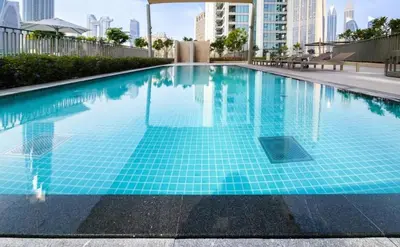 a swimming pool with blue tiles in a city at Chic & Classic 1BDR In Downtown Views-14 in Dubai