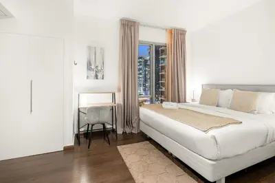 a white bedroom with a large bed and a window at FIRST CLASS 1BR Luxury Marina View Escape in Dubai