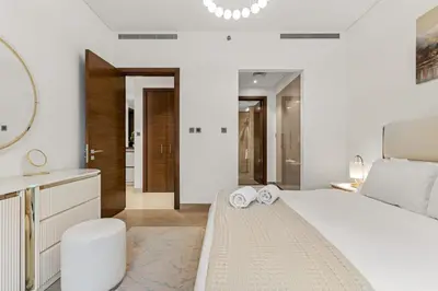 a white bedroom with a large bed and a bathroom at FIRST CLASS 1BR Luxe Hideaway Escape in Dubai