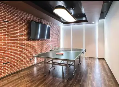 a ping pong table in an empty room with a brick wall at have fun with your family and friends in our apt in Dubai