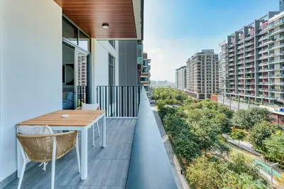 a balcony with a table and a view of a city at PVH - Kensington Waters - Lavish 1BR - Park Front in Dubai