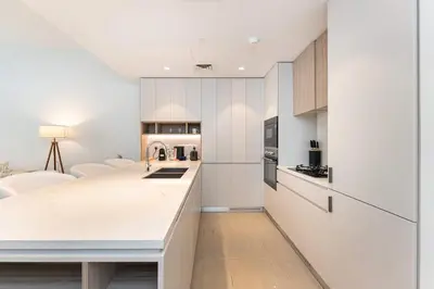 a kitchen with white cabinets and a white counter top at PVH - Kensington Waters - Lavish 1BR - Park Front in Dubai