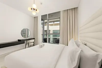 a white bedroom with a large white bed with white pillows at FIRST CLASS 1BR Relaxing Urban Escape in Dubai