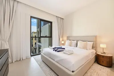 a white bedroom with a large bed and a window at Luxury 1BR Beach Access Creek Beach in Dubai