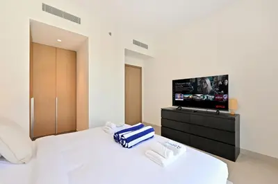 a bedroom with a white bed and a flat screen tv at Luxury 1BR Beach Access Creek Beach in Dubai
