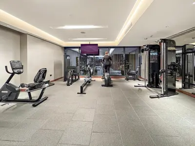 a gym with cardio equipment and a man in the background at FIRST CLASS 2BR Classy Getaway Near Downtown in Dubai