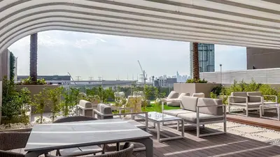 a patio with chairs and tables on top of a building at Stylish Studio with Modern Comfort & Luxury - 2AB06 in Dubai