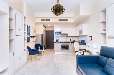 a living room with a blue couch and a kitchen at Burj Khalifa view cozy studio in Dubai