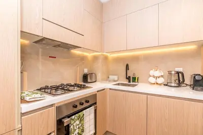 a kitchen with wooden cabinets and a stove top oven at Modern & Cozy JVC Studio Couple or Solo in Dubai