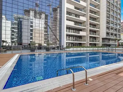 a large swimming pool with tall buildings in the background at Stylish City Studio with Balcony View in Meydan in Dubai
