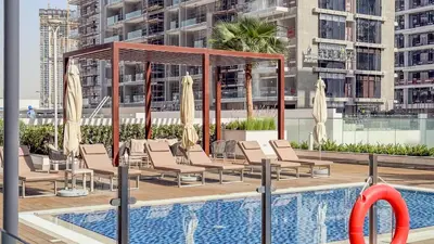 a pool with lounge chairs and a gazebo at TRPS - Azizi RIviera 63, Al Meydan - Brand New Studio, Modern Furnished, Excellent Amenities in Dubai