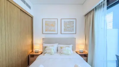 a bedroom with a large bed with two lamps at TRPS - Azizi RIviera 63, Al Meydan - Brand New Studio, Modern Furnished, Excellent Amenities in Dubai