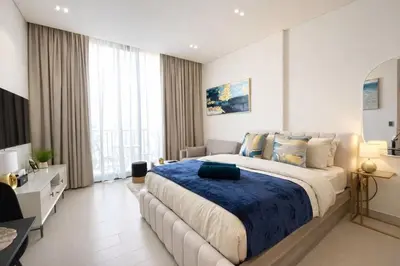 a bedroom with a large bed with a blue blanket at Premium Studio W Pool & Gym Binghatti Aurora in Dubai