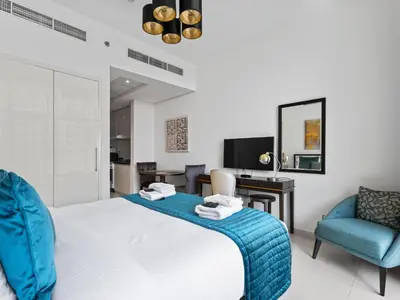 a bedroom with a bed and two chairs and a desk at Exquisite Lavish Studio in Ghalia JVC -16 in Dubai