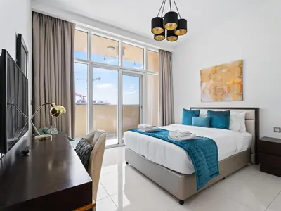 a bedroom with a bed and a desk and a window at Exquisite Lavish Studio in Ghalia JVC -16 in Dubai