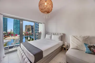 a bedroom with a bed and a couch and a large window at Daniels Studio with Lake View in JLT in Dubai